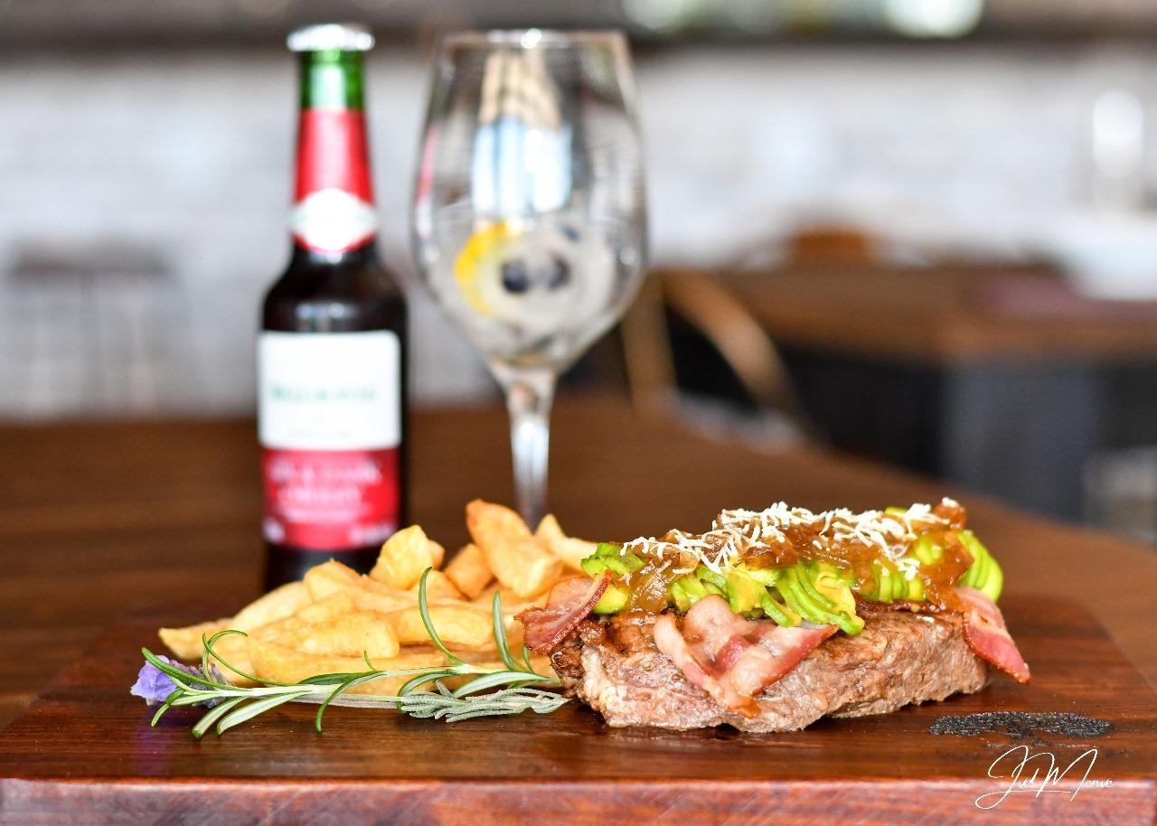 Steak topped with avocado and cheese, with chips