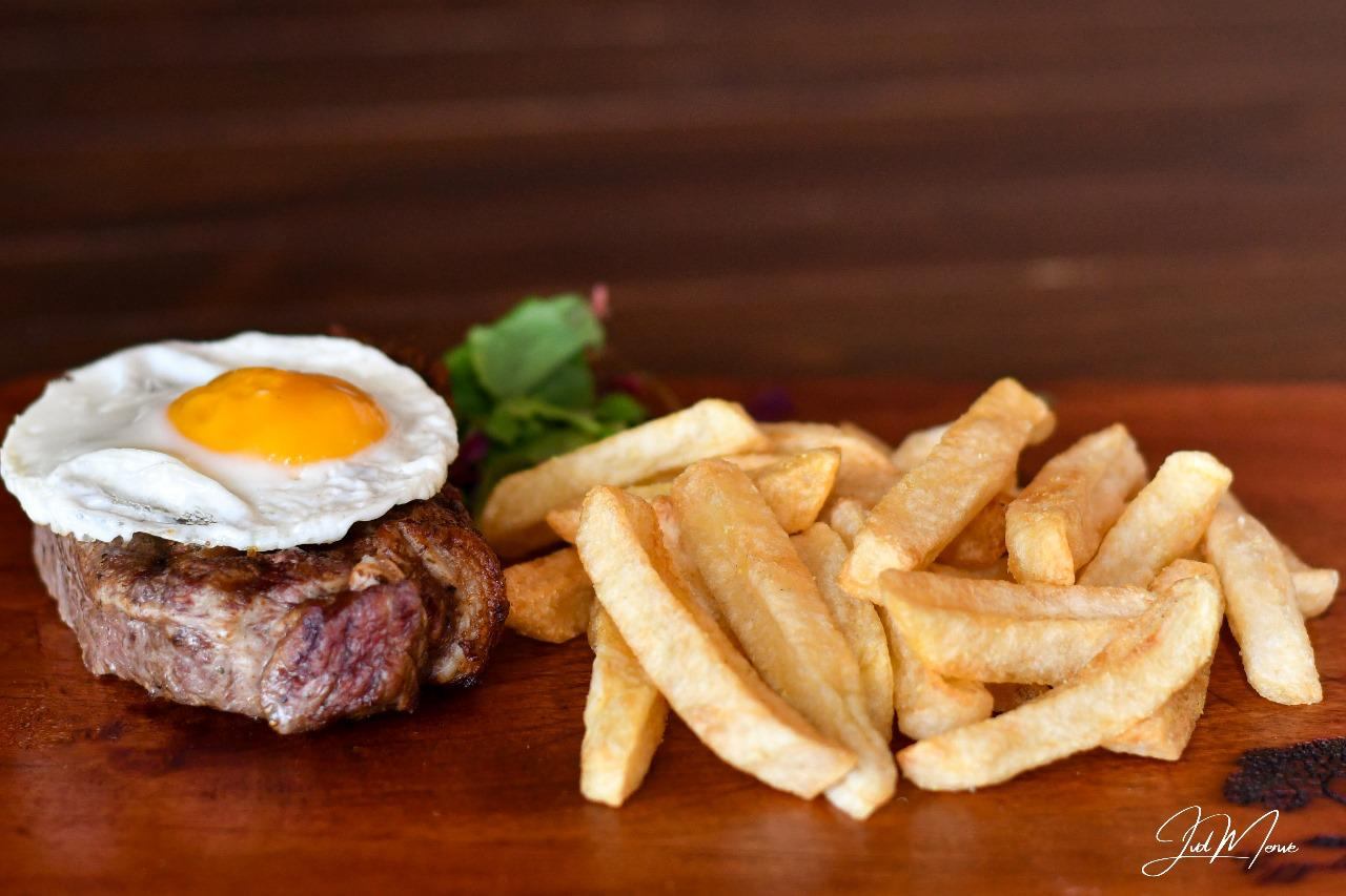Steak topped with a fried egg, served with chips